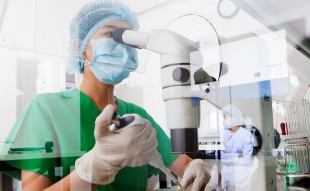 Medical worker using a powerful microscope to guide injection