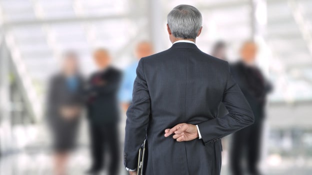 Superstitious man in suit with fingers crossed