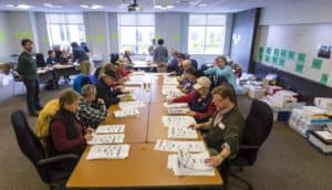 People sitting around a large table counting votes by hand