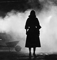 Silhouette of the back of a woman standing, gazing into fog