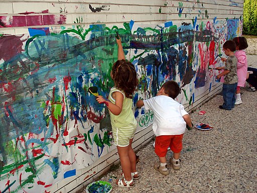 Young students painting on a wall