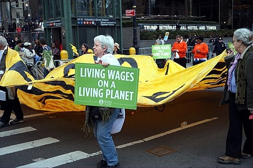 Photo of woman carrying a poster saying, Living Wages on a Living Planet.